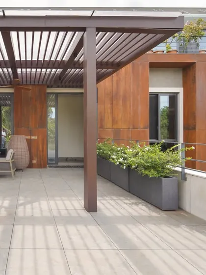 A view of the expansive terrace at the U-L-I Residence, featuring a pergola that casts geometric shadows. We design these outdoor spaces as seamless extensions of the interior, providing private retreats that are visually connected to the home's overall architecture.