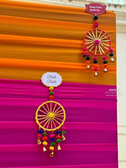 Fun and colorful dreamcatcher-style hangings with pom-poms and bells, adding a playful element to the Mehendi decor.