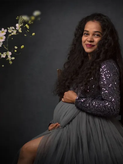 Another example of a fine-art maternity portrait. The soft lighting and floral accents add a touch of delicate beauty to this seated pose, highlighting her joyful anticipation.