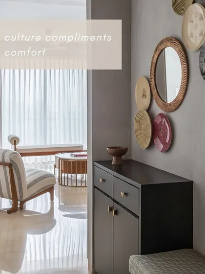 The entrance foyer of 'House Nandini' is where culture complements comfort. A curated collection of decorative plates and a mirror creates an artistic focal point against the textured grey wall.