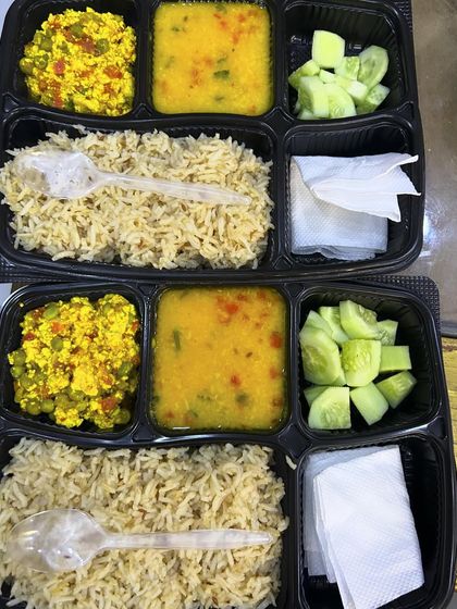 Two diet thalis ready for delivery. This meal includes paneer bhurji, dal, and brown rice, with a side of fresh cucumber salad.