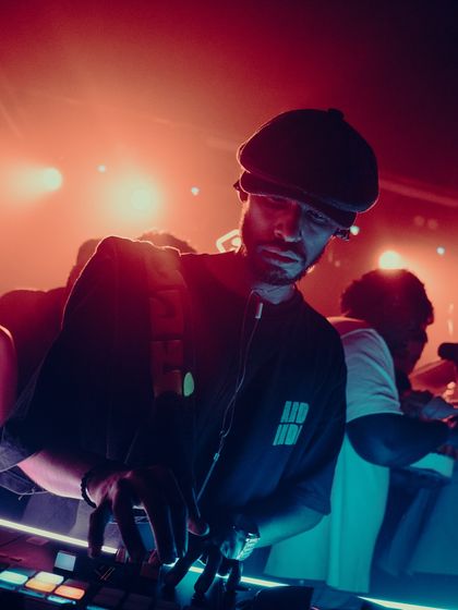 A close-up shot of me at the decks during a packed club night. The red lighting and intense focus capture the heat of the moment.