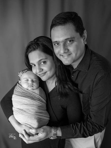 A classic family portrait in black and white. The focus is entirely on their happy expressions and the love they share for their new baby.