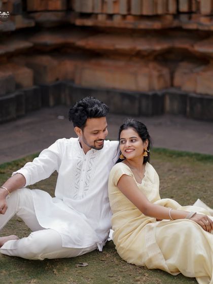 A happy, candid moment between a couple in traditional wear, seated on the grass with a temple backdrop. My goal is to capture your genuine smiles and interactions.