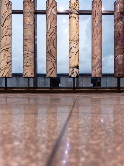 A close-up of the prayer wheel art installation, reflecting on the polished terrazzo floor. This piece harmonizes modern industrial design with cultural significance, creating a peaceful, welcoming environment.