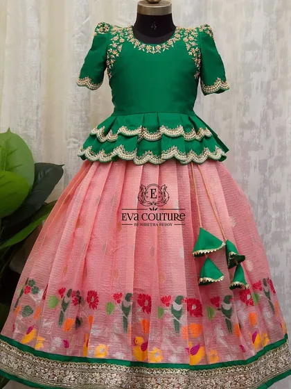 This lehenga features a pink organza skirt with a colorful bird and floral print border. The green peplum blouse has matching embroidery.