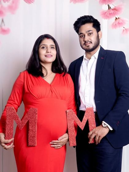A fun pregnancy announcement shot with the couple holding sparkling 'MOM' letters. Props like these add a playful and personal touch to your studio maternity session.