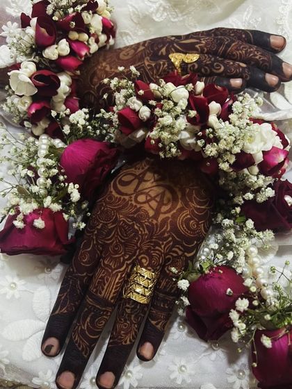 A gorgeous bridal shot where the custom initial 'A' is visible, perfectly accessorized with floral bracelets and gold rings.