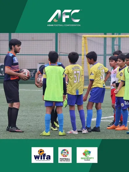 A coach giving instructions to a group of young players at the AFC Grassroots Day.