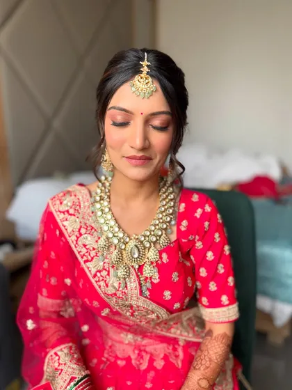 A serene moment with eyes closed, highlighting the soft, shimmery eyeshadow and the overall minimalist approach to this red bridal look.