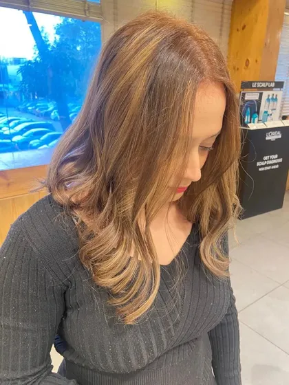A beautiful hair color transformation that resulted in this warm, golden-toned style, perfect for brightening up her look.