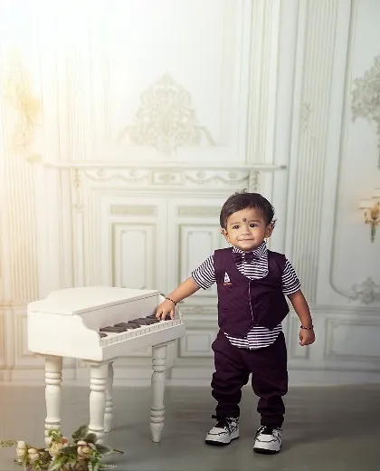 Piano keys and cheeky grins make the perfect duet. This little gentleman looks so sharp standing by his miniature grand piano.