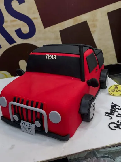 For the auto enthusiast, we crafted this 3kg cake meticulously sculpted into a vibrant red Thar jeep. Every detail, from the grille and wheels to the license plate, is handcrafted from fondant, demonstrating our skill in creating realistic 3D vehicle cakes.