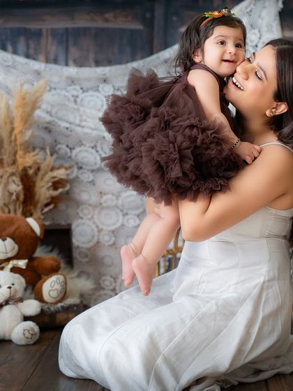 A mother and daughter sharing a big hug in the studio. The rustic, cozy setup with teddy bears makes for a warm and inviting scene.