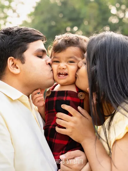 Let's chase the beautiful 'golden hour' light together. Outdoor sessions in a lovely garden setting allow for natural, playful, and warm photographs. A family kiss-sandwich like this is the perfect way to capture your family's fun-loving spirit.