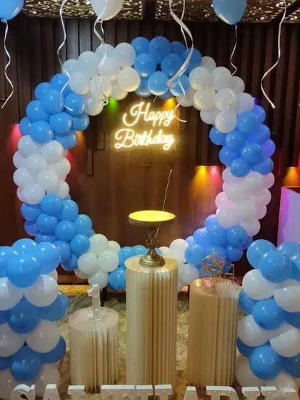 A blue and white balloon ring with pedestals and a neon sign.