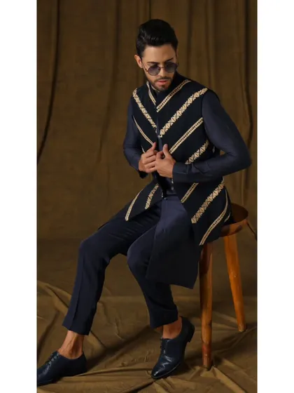 The Nilo Pushpak bandi set. A regal midnight blue bandi jacket with coffee-golden diagonal wire work, paired with a royal blue kurta and trousers for a deeply sophisticated look.