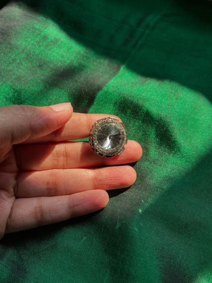 A classic oversized ring with a large central crystal, designed to catch the light and draw attention.
