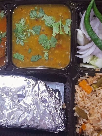 A colorful and nutritious thali with vegetable pulao, aloo kofta curry, and dal. A complete and balanced meal in one box.