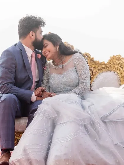 A closer portrait of the couple on a beautiful ornate bench. The groom's tender kiss on the bride's forehead and her happy smile capture a perfect moment of intimacy.