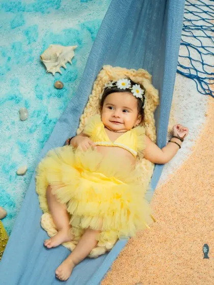 An overhead view of our little beach baby lounging in her hammock. This angle highlights the entire setup, including the faux water, sand, starfish, and fishing net props.