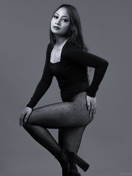 A dynamic black and white pose, with the model's leg raised, showing strength and style.