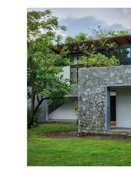 The 'Villa in a Grove' under a cloudy monsoon sky. The stone walls and green roof help the building merge with the verdant landscape.