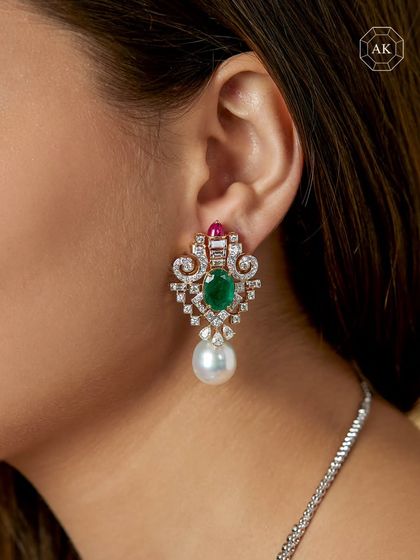 These striking earrings feature emeralds, rubies, and a blend of baguette and round diamonds, anchored by luminous South Sea pearls.