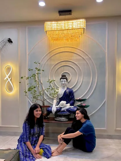 Two happy clients sitting in front of a serene Buddha installation.