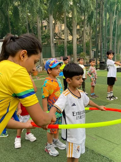 A coach guides a child through a hula hoop exercise. We provide one-on-one attention to help kids learn new skills and build their physical confidence.