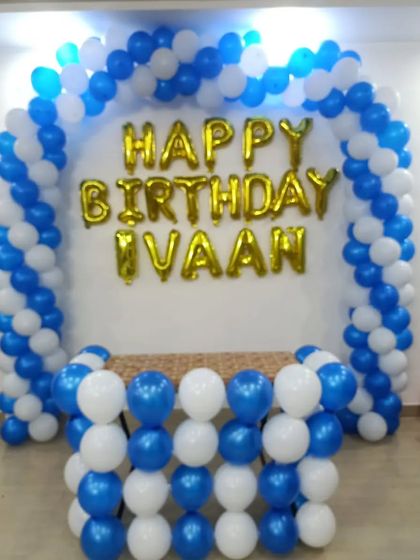 A classic blue and white balloon arch with gold foil letters spelling "Happy Birthday Ivaan," perfect for a simple and clean look.