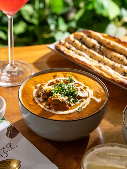 A bowl of rich butter chicken with fresh cream and cilantro. The bright, natural light makes the colors of the curry pop.