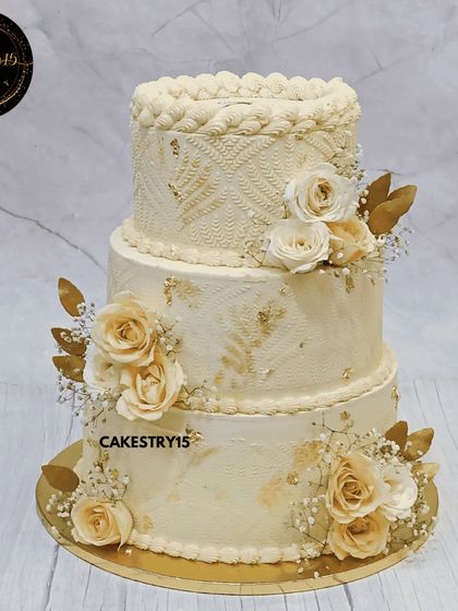 A grand 10kg, three-tier corporate anniversary cake. This elegant masterpiece features an ivory color scheme, intricate engraving, and is adorned with ivory roses and golden leaves.