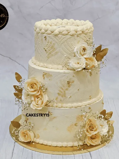 A grand 10kg, three-tier corporate anniversary cake. This elegant masterpiece features an ivory color scheme, intricate engraving, and is adorned with ivory roses and golden leaves.