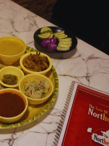 A simple, satisfying thali meal. This shows the different components in their bowls, including dal, a dry vegetable, chutney, and Aloo Pitika, ready to be enjoyed.