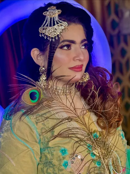 A creative portrait using a peacock feather as a prop to complement the colors in the makeup and outfit.