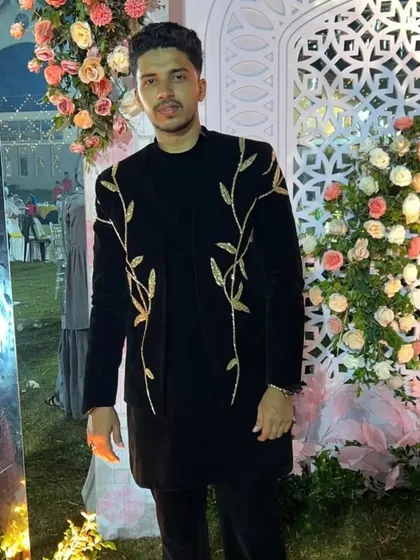 A client at an event in a black velvet open jacket with simple gold vine embroidery. A classic and versatile piece.