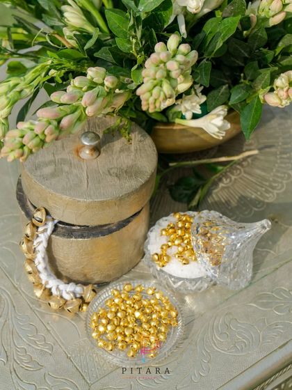 A close-up of traditional decor elements, including ghungroos and gold beads, arranged beautifully on a silver table.