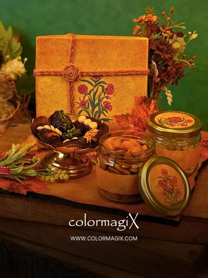 An autumnal-themed tray hamper perfect for Diwali. It features a beautiful hand-painted box, jars of dry fruits, and a bowl of dates, all arranged on a rustic wooden platter.