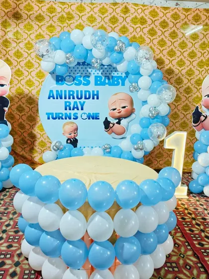 This Boss Baby first birthday setup features a custom backdrop, character pillars, and a balloon-decorated table for the cake. It's a popular theme for a boy's first birthday party.