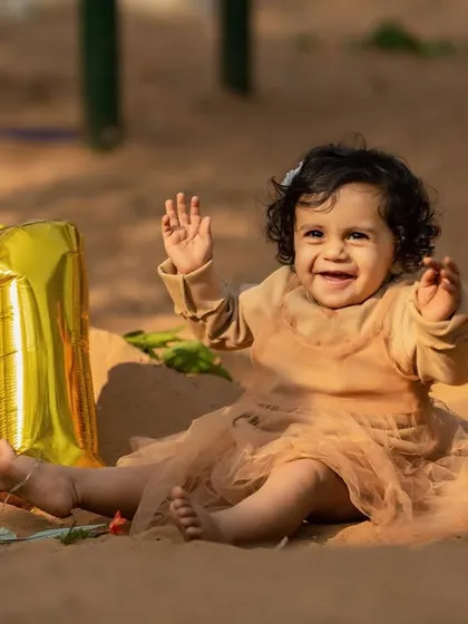 Turning one is a big deal. This happy baby, sitting in the sand with her "1" balloon, is all smiles. Outdoor milestone sessions are a wonderful way to celebrate.