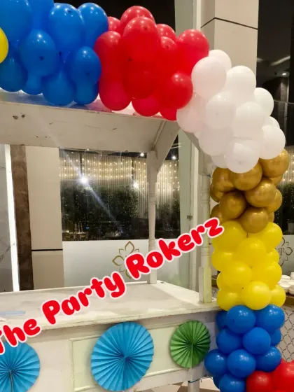 A food cart decorated with a colorful balloon garland, perfect for a carnival or circus-themed party.
