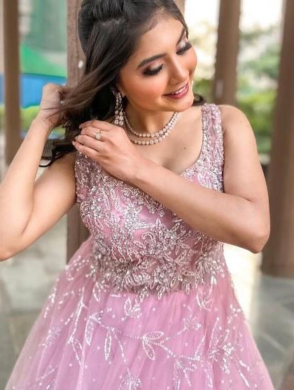 A candid moment in the pink reception gown, showing the delicate silver embroidery and the soft tulle fabric of the skirt.