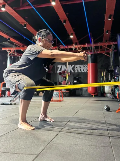 A client uses a resistance band to add a challenge to her squat. Bands are a great tool for activating the glutes and improving hip stability during workouts.