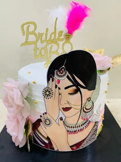 A chic and modern cake for a bride-to-be. This design features a stylish bridal illustration, delicate pink flowers, and elegant feather toppers for a memorable bridal shower.