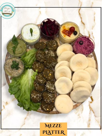 Our vegetarian Mezze Platter is a vibrant spread of Mediterranean delights. It features falafel, mini pitas, and a variety of colorful dips like hummus and baba ghanoush, perfect for sharing.