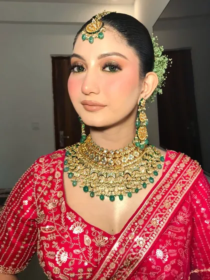 A beautiful shot of the bride, showcasing her heavy kundan and emerald choker and matching maang tikka. The fresh gajra in her hair adds a soft touch.