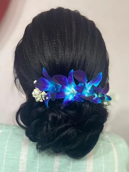A back view of the floral bun, showing the placement of the vibrant blue orchids and baby's breath.