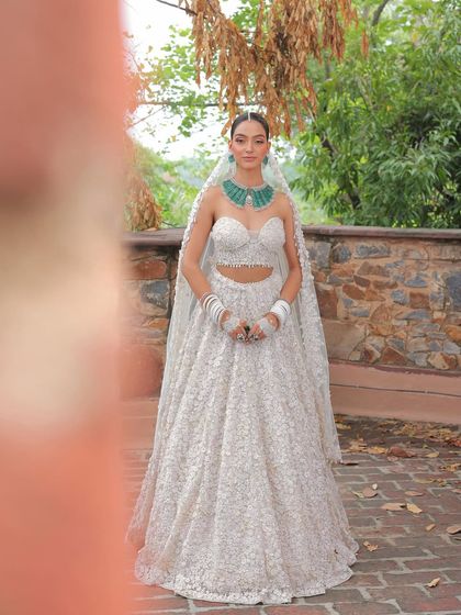 A full-length shot of the dainty bride in her white lehenga. The look is ethereal and angelic, with a focus on softness and elegance.