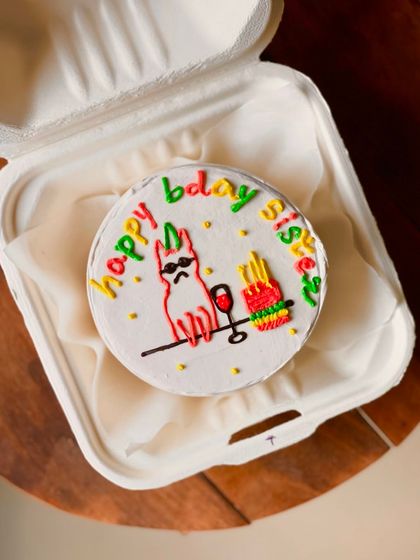 A fun and colorful birthday cake for a sister, featuring a cool cat with sunglasses, a glass of wine, and fries. The multi-colored "happy bday sis" text adds to the playful vibe.